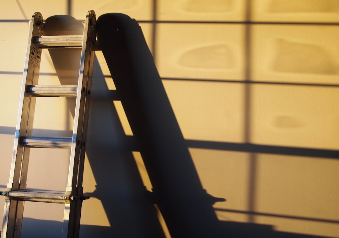 A metal ladder casting a shadow on a wall, illustrating a home improvement theme