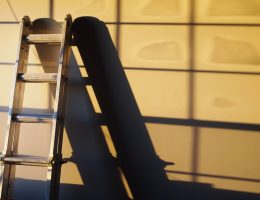 A metal ladder casting a shadow on a wall, illustrating a home improvement theme