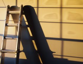 A metal ladder casting a shadow on a wall, illustrating a home improvement theme