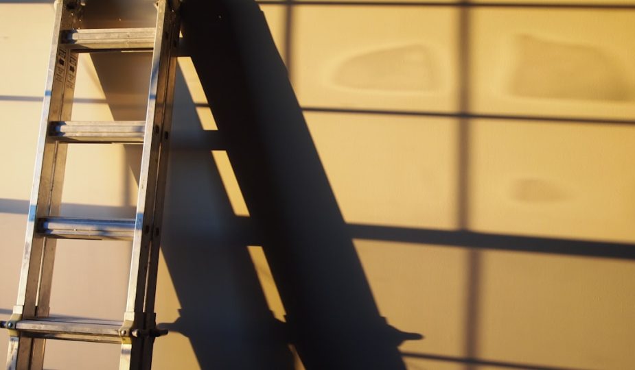 A metal ladder casting a shadow on a wall, illustrating a home improvement theme